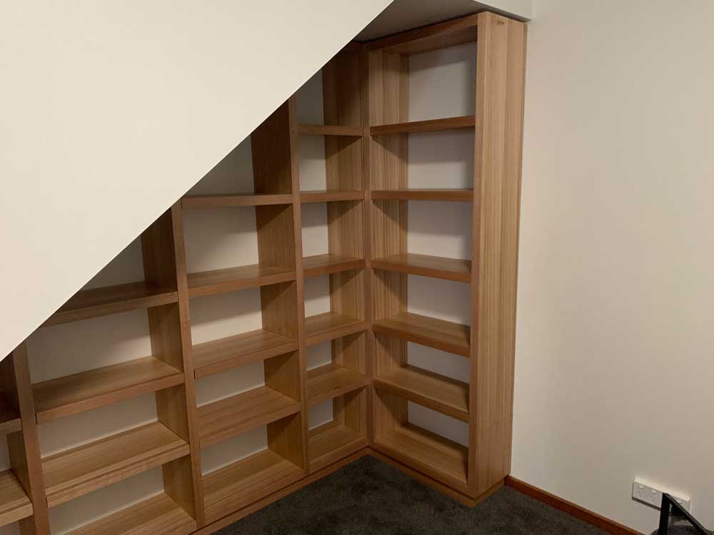 Custom Tasmanian Oak bookcase fitted into an under-stairs corner
