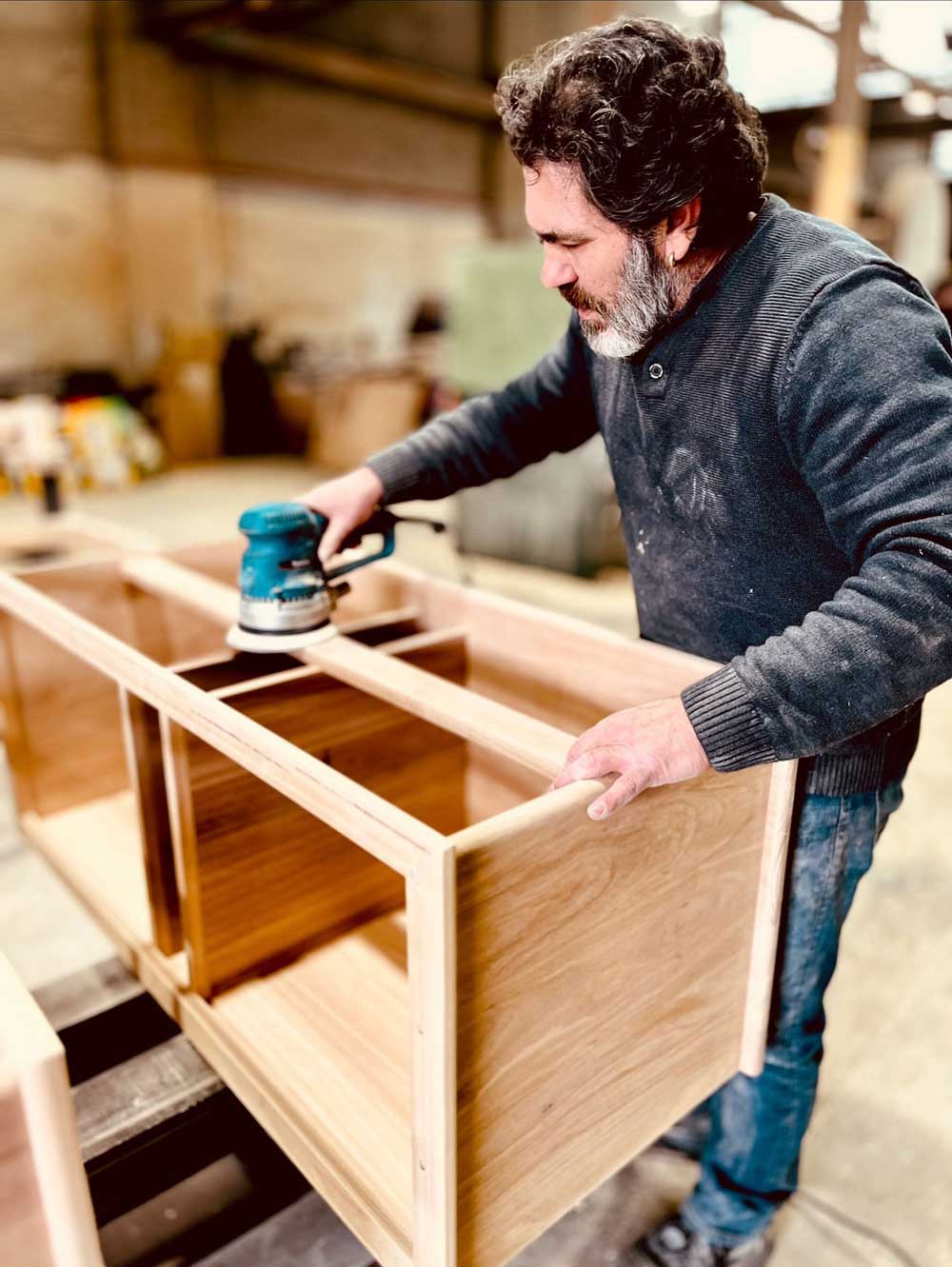 Don sanding a custom timber cabinet frame in the Pride Furniture workshop